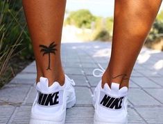 a woman's foot with a palm tree tattoo on her left side and the word nike written in black ink