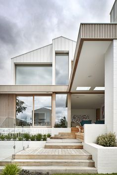 a modern house with large windows and steps leading up to the front door that lead into the back yard