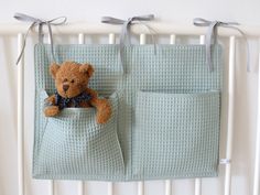 a teddy bear sitting in the pocket of a crib