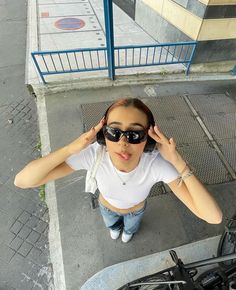 a woman wearing sunglasses standing next to a bike