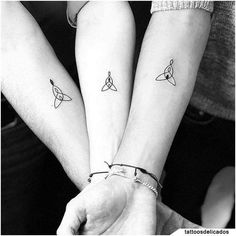 two people holding hands with tattoos on their arms