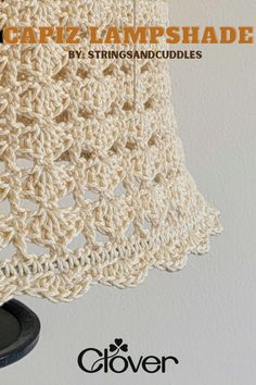 a crocheted lamp shade hanging from the ceiling in front of a white wall