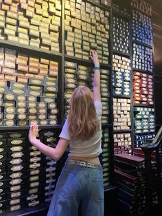 a woman standing in front of a wall filled with lots of different types of coins