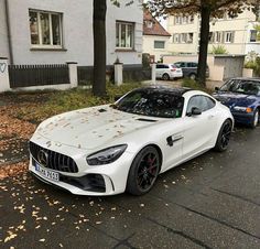 a white mercedes sports car parked on the side of the road in front of some houses