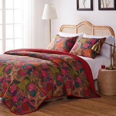 a bed with colorful bedspread and pillows in a room