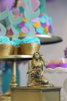 there are cupcakes and cakes on the table with little mermaid figurines