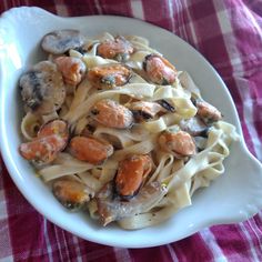 pasta with shells and carrots in a white bowl on a checkered table cloth