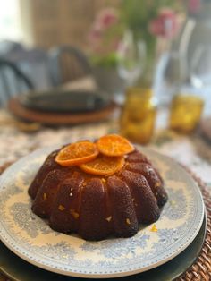 a bundt cake with sliced oranges on it sitting on a blue and white plate