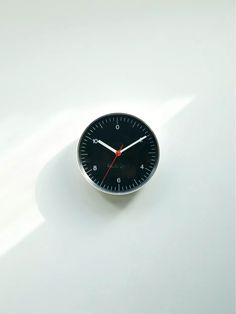 a black clock sitting on top of a white table next to a red second hand