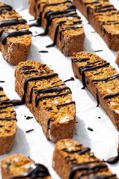 desserts with chocolate drizzled on them are lined up in rows and ready to be eaten