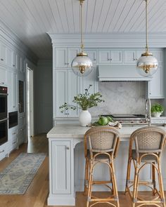 two stools sit in front of an island with marble countertops and white cabinets