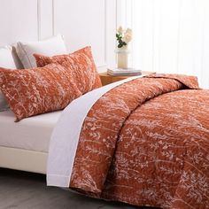 a bed with an orange comforter and white pillows