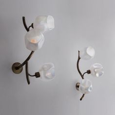 two wall lights with white glass shades on the bulbs and one light is turned off