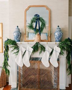 stockings hung on the mantle in front of a mirror and fireplace mantel decorated with greenery