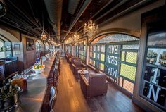 an empty restaurant with lots of tables and chairs in front of the windows that have stained glass on them