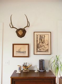 there are two pictures on the wall with deer heads above them and a coffee maker