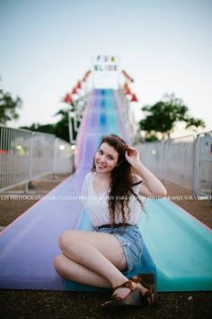 a woman sitting on top of a slide at an amusement park