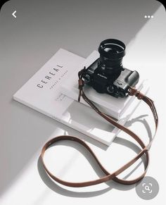 a camera sitting on top of a white box next to a brown leather strap,