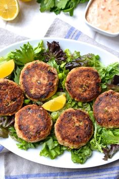 crab cakes on a plate with lettuce and lemon wedges