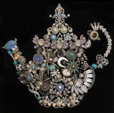 an elaborately decorated teapot with pearls, jewels and other things in it on a black background