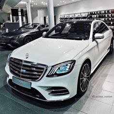 two white cars are parked in a showroom