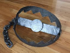 a metal object sitting on top of a wooden floor next to a chains attached to it