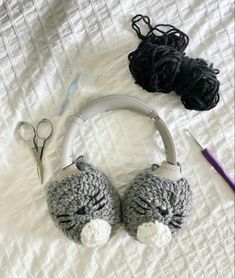 crocheted animal headphones and scissors on a bed with yarn, thread and knitting needles