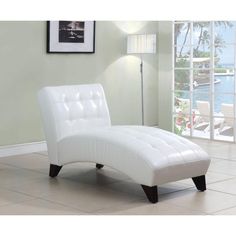 a white chaise lounge chair sitting in front of a window