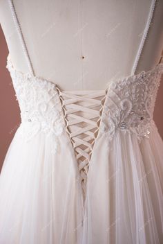 the back of a white wedding dress with flowers on it's waist and straps