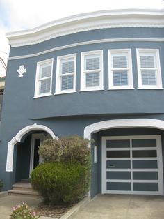 a blue house with white shutters and two cars parked in front of the garage