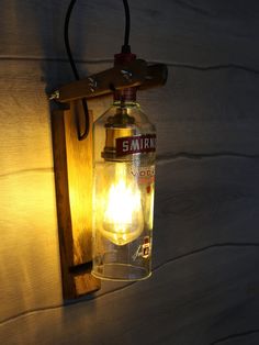 a light that is on the wall next to a wooden frame with a bottle in it