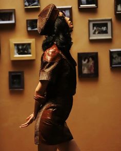 a woman is standing in front of many framed pictures