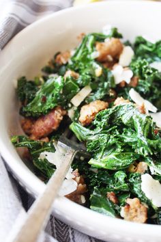 a white bowl filled with spinach and meat on top of a striped table cloth