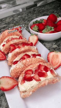 sliced strawberries and cream cheese sandwich on a white plate next to a bowl of strawberries