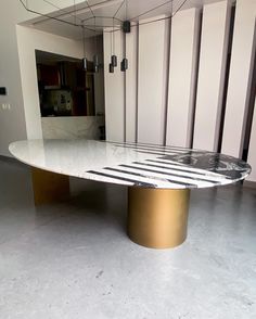 an oval table in the middle of a room with white walls and gold trimmings