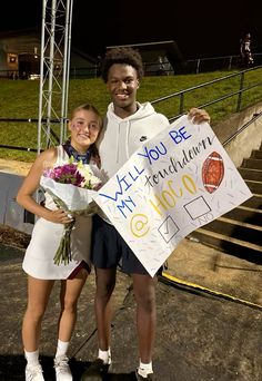 two young people standing next to each other holding flowers and a sign that says, i will you be my birthday?