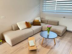 a living room with a couch, table and window in the corner that has blinds on it