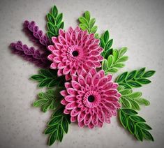 three pink flowers with green leaves on a white table top, one is made out of paper and the other has scissors