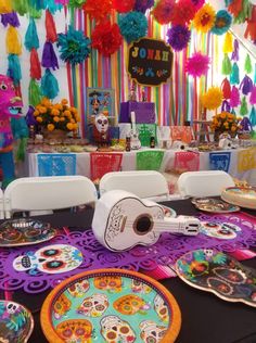 a table topped with plates covered in sugar skulls and paper streamers hanging from the ceiling