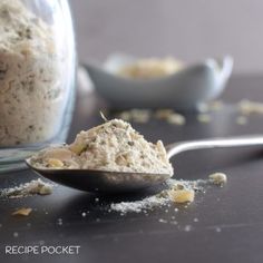 a spoon full of food sitting on top of a table next to a glass jar