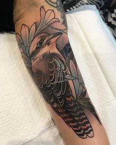 an arm with a bird and feathers tattoo on it