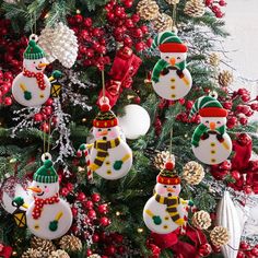 a christmas tree with ornaments hanging from it's branches and snowmen on top