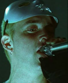 a man wearing a silver hat and holding a microphone to his mouth with one hand