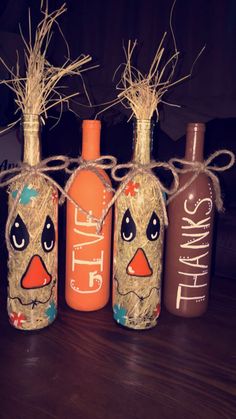 three wine bottles with faces painted on them and twine tied to each other, sitting on a table