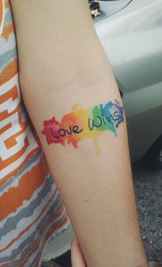 a woman's arm with the word love written in watercolors on it