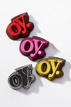 three different types of brooches on a white surface with the word joy spelled in red, yellow and black