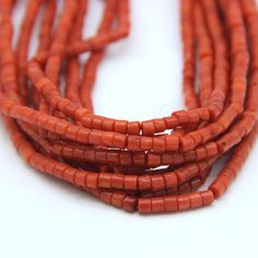 red coral beads are lined up on a white surface