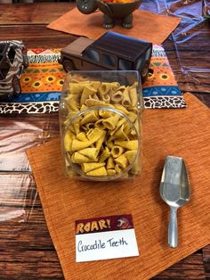 a bowl of pasta sits on a place mat next to a fork, spoon and napkin