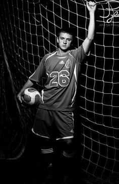 a man holding a soccer ball in front of a net with the number 26 on it