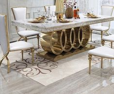 a dining room table with white chairs and gold accents